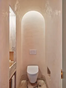 A modern bathroom with marble finishes and an arched doorway.