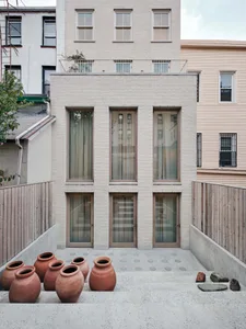 Modern brick townhouse exterior with large windows and terracotta pots in the foreground.