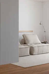 Modern minimalist living room featuring a comfortable, textured fabric seating area and a sleek, industrial-style floor lamp.