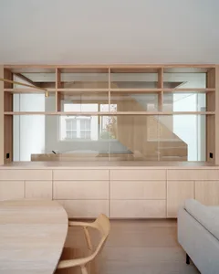 A minimalist living room with wooden furniture and shelves.