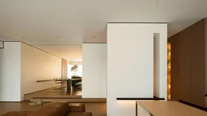 Modern, minimalist living room with white walls, wooden flooring, and a sleek, low-profile furniture arrangement.
