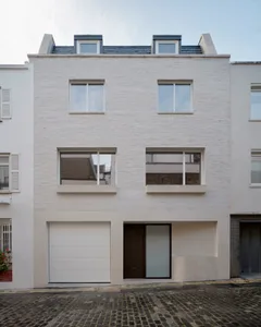 A modern, white-brick residential exterior with brick roofing, large windows, and a garage door.