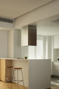 A modern white kitchen features a bar stool counter with two stools.