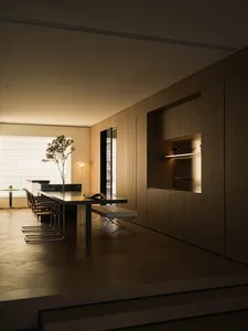 A modern, minimalist residential kitchen featuring wooden finishes, clean lines, and a sleek, understated design.