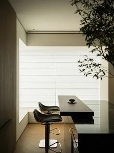 Modern kitchen with wooden counters, black leather stools, and glass window.