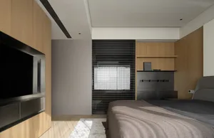 Minimalist bedroom featuring a large bed with wooden elements and a wooden floor, illuminated by natural light from a window.