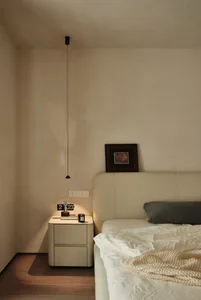 A minimalist bedroom with a bed, nightstand, and artwork on the wall.