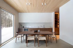 A modern kitchen with wooden cabinetry and a large window showing a snowy landscape.