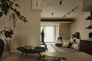 A cozy modern living room featuring a plush sofa, a low coffee table, and a minimalistic clock on the wall.