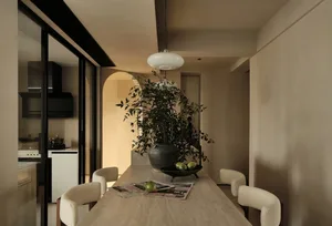 Marble dining table with chairs, plants, and a bowl of green fruits in a modern interior setting.