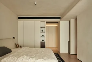 A minimalist bedroom with white and beige furniture and a simple, clean design.