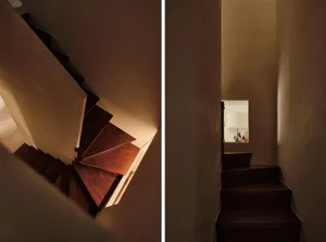 A modern staircase with dark wooden steps and a wall-mounted light fixture.
