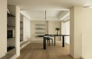 A minimalist home office featuring a black metal table and a vase of greenery.