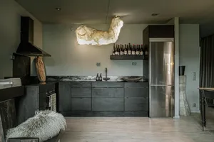 A modern minimalist kitchen featuring black cabinets and a marble countertop.