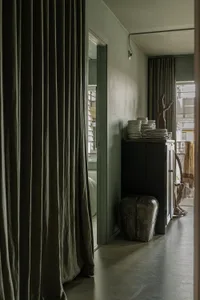 A minimalist room with textured plaster walls and a rugged, rustic furniture piece, featuring a natural wood cabinet and a co