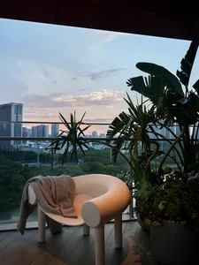 Modern balcony featuring a city view with potted plants and a wooden deck.