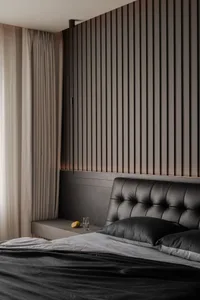A bedroom with a modern design featuring a black leather headboard, wooden material, and neutral color palette.
