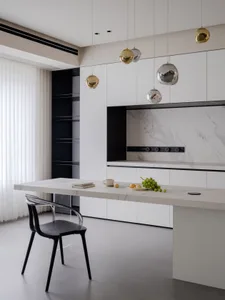 Modern kitchen featuring a marble countertop with a black chair, hanging lights, and a marble backsplash.