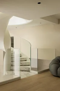 A modern interior featuring a marble staircase with glass railings and lighting.