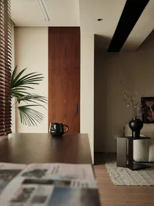 A modern minimalist apartment with wooden doors, fabric seating, and metal accents.