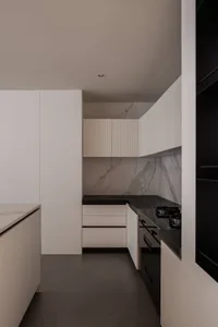 A modern residential kitchen featuring white marble countertops and cabinets.