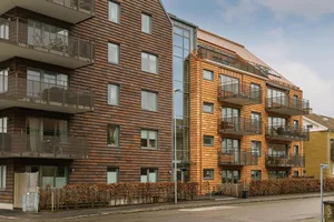 Photo of modern residential apartments with wooden exteriors and glass balconies.