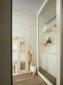 A white indoor cat playroom featuring climbing structures and shelves with a white cat inside.