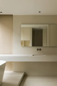 A minimalist bathroom with white ceramic tiles, a large mirror, and a freestanding bathtub.