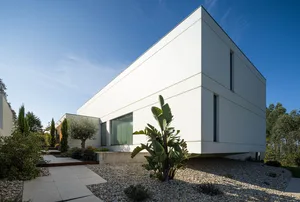 A modern architectural exterior with a minimalist design featuring concrete walls and large windows.