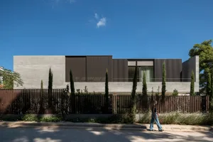 Modern minimalist house featuring concrete exterior and large windows.
