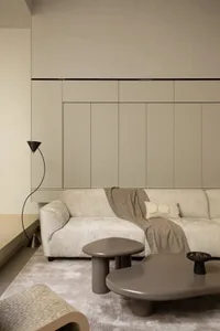 A minimalist living room with a sofa, coffee tables, and a floor lamp.