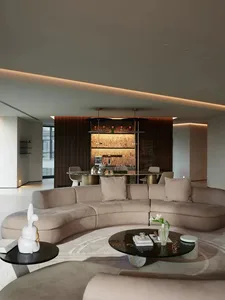 Modern interior living room with a curved sofa in neutral tones and a round glass table.