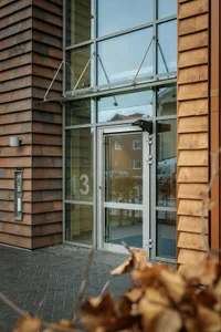 An exterior view of a modern office building featuring glass windows and wooden exterior siding.