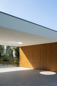 A modern architectural exterior featuring wooden panels, tiled floor, and concrete elements.