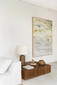 A modern white sofa with a wooden coffee table featuring a lamp and decorative items.