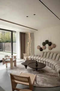 Modern interior design featuring a living room with neutral-toned, textured furniture and a distinct wall art piece.
