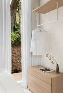 A minimalist closet interior featuring white Sherwood wood furniture and a white t-shirt hanging on a white hanger.