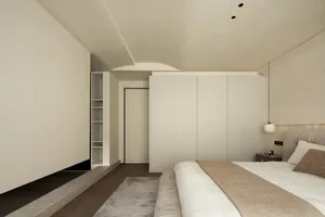 A modern bedroom featuring white walls and a large bed.