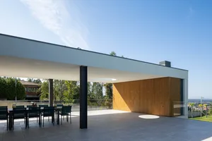 A modern residential veranda with concrete flooring and wooden walls.