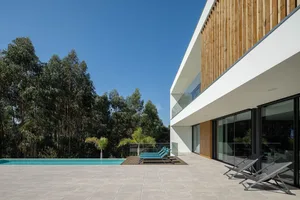 Modern house exterior featuring concrete, glass, and wooden elements.