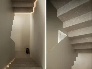 A modern staircase with white terrazzo tiles and hidden lighting features a vase at the bottom.