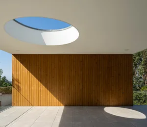 Modern wooden exterior with a geometric design featuring a round skylight and textured wood paneling.