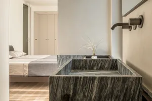 Modern minimalist bedroom interior featuring a textured marble sink and sleek design elements.
