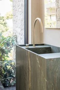 Minimalist modern bathroom with grey marble sink and gold faucet.