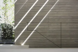 Modern concrete staircase with minimalist black railing and sunlight filtering through the window.