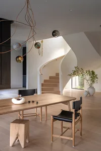 Modern residential dining room featuring wooden dining table and leather chairs.
