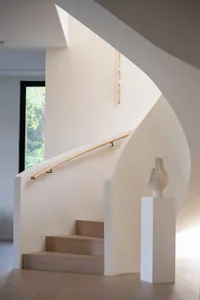 A modern staircase with white walls, wood steps, and a wooden handrail.
