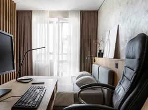 Modern minimalist bedroom with a black leather office chair, white bedspread, and white curtains by the large window.