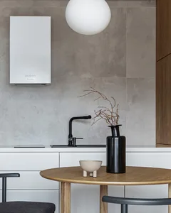 Modern minimalist kitchen featuring a round wooden table, black stools, and a concrete tile backsplash.