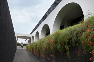 Modern architectural design featuring a concrete structure with a greenery-covered wall and garden.